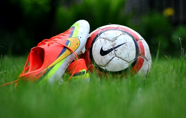 Футбольный мяч и бутсу на зеленой траве