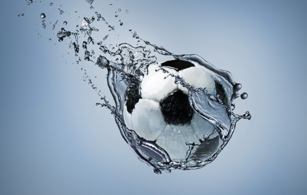 Футбольный мяч летит в воде на сером фоне