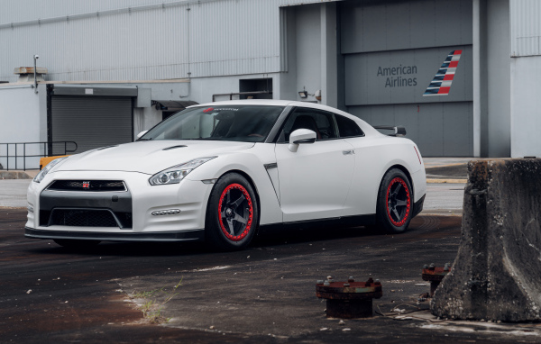 Белый автомобиль Nissan GT-R у гаража