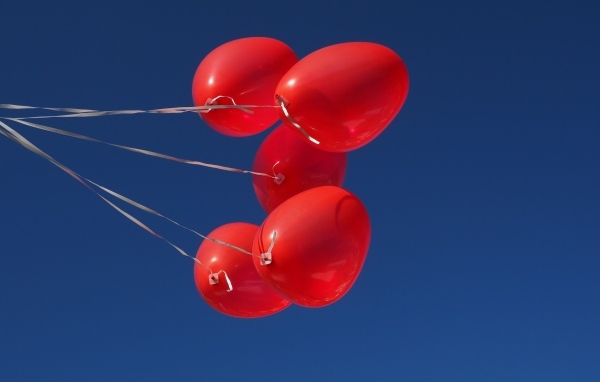 Красные воздушные шары на нитке на фоне голубого неба