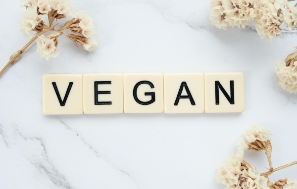 Надпись веган на столе с цветами