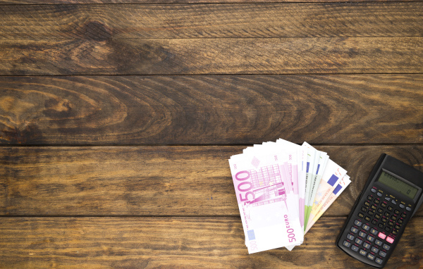 Купюры и калькулятор на деревянном фоне