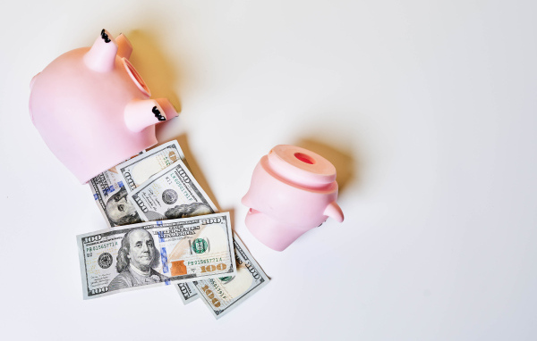 Разбитая свинья копилка на сером фоне с долларами