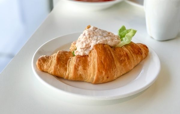 Круассан с начинкой на белой тарелке на завтрак 