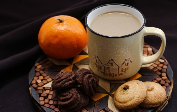 Чашка какао на тарелке с мандарином и печеньем