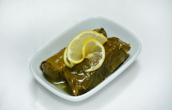 Долма с лимоном с тарелке на сером фоне