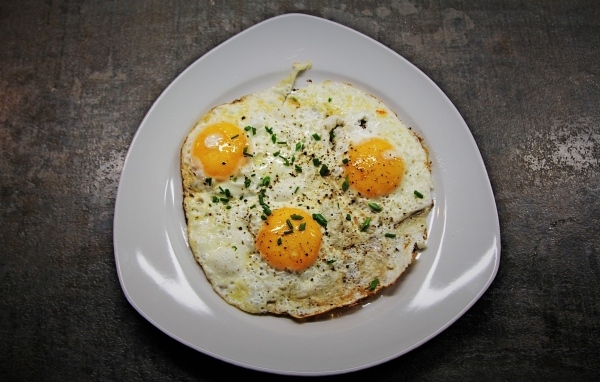 Яичница глазунья в тарелке на сером столе