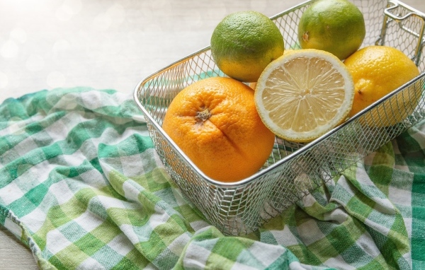 Цитрусовые фрукты в железной корзине на столе