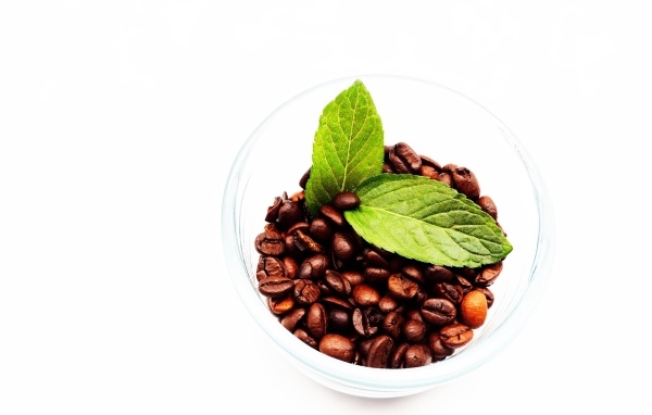 Стакан с кофейными зернами и листьями мяты