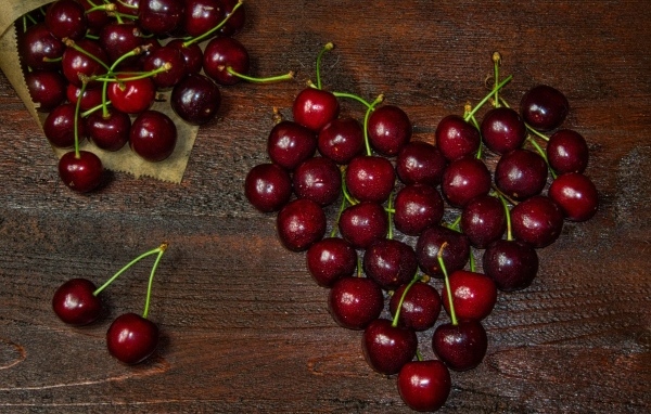 Сердце из спелых ягод черешни на деревянном столе