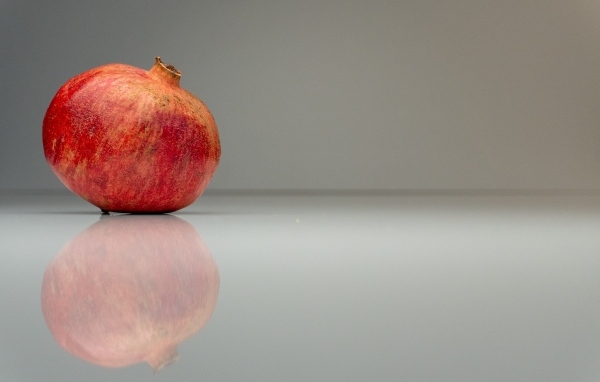 Красный гранат отражается в поверхности на сером фоне