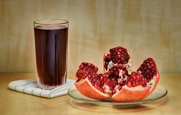 Красный гранат на столе со стаканом сока
