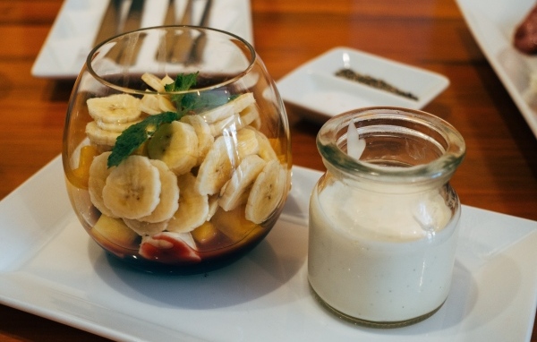 Нарезанные бананы в стакане на столе с йогуртом