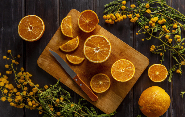 Нарезанный апельсин на доске на столе с цветами