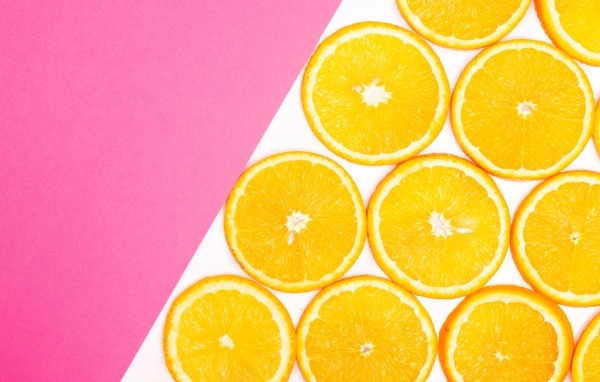 Нарезанный апельсин на бело-розовом фоне