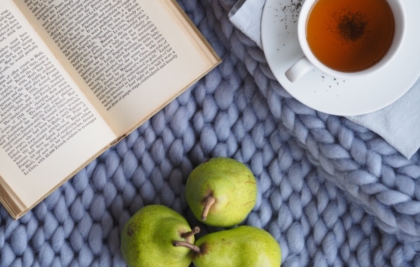 Три зеленые груши на столе с чаем и книгой