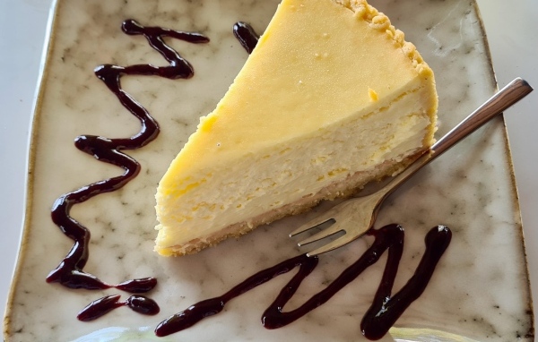 Кусок чизкейка с шоколадным топпингом на тарелке