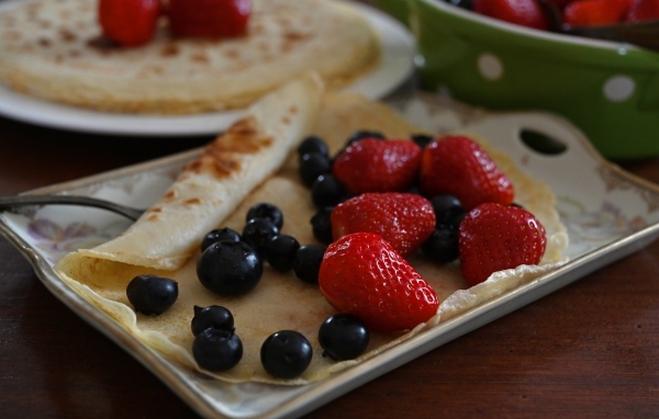 Блин с ягодами черники и клубники на тарелке