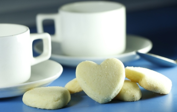 Сладкое печенье в форме сердца с кружками на столе