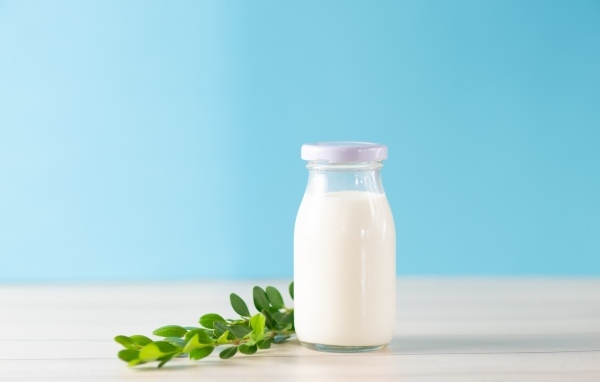 Бутылка молока с листьями на голубом фоне