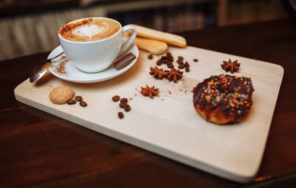 Чашка кофе на доске со специями и печеньем