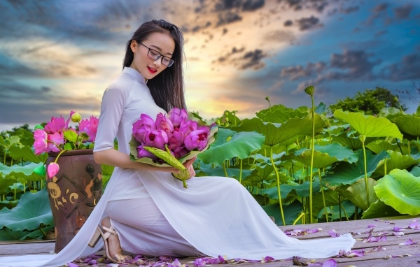 Девушка азиатка в белом платье с цветами лотоса