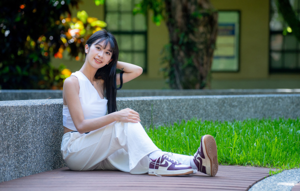 Девушка азиатка в белой костюме сидит на земле