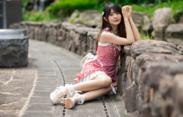 Азиатка сидит на земле в красном платье