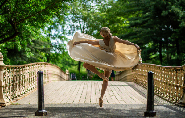 Девушка балерина в стойке на мосту
