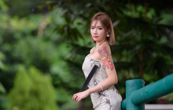 Красивая девушка азиатка с татуировкой на руке