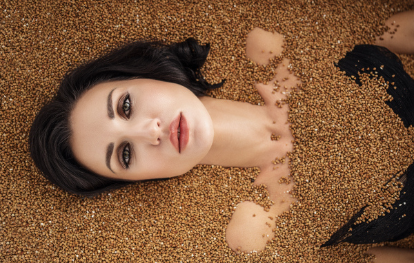 Красивая девушка лежит в зернах гречки