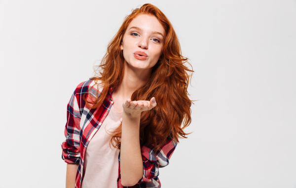 Красивая рыжеволосая девушка шлет воздушный поцелуй