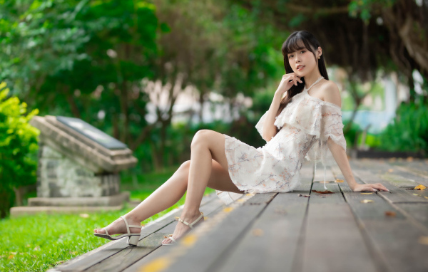 Симпатичная молодая азиатка сидит на деревянном покрытии