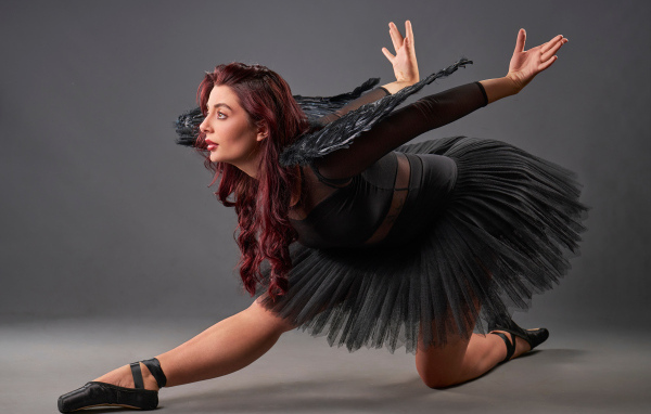 Девушка в черном костюме с крыльями танцует