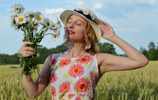 Девушка с букетом ромашек на поле