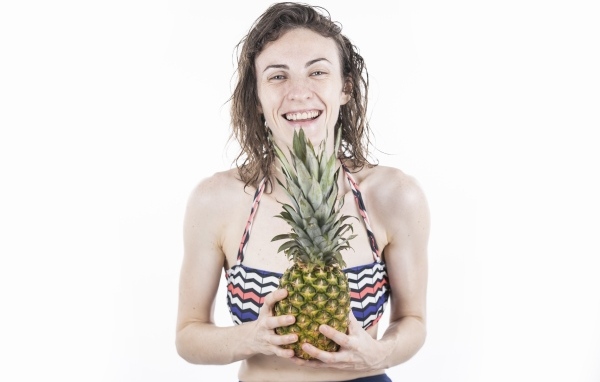 Улыбающаяся девушка с ананасом в руках