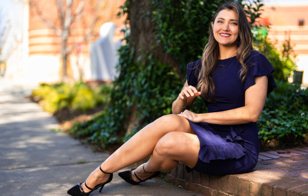 Улыбающаяся женщина в синем платье сидит на земле