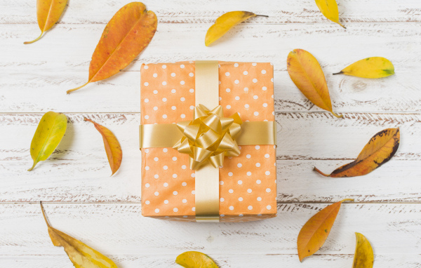 Подарок с желтыми листьями на белом фоне