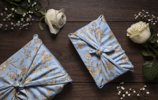 Два подарка с белыми розами на деревянном столе