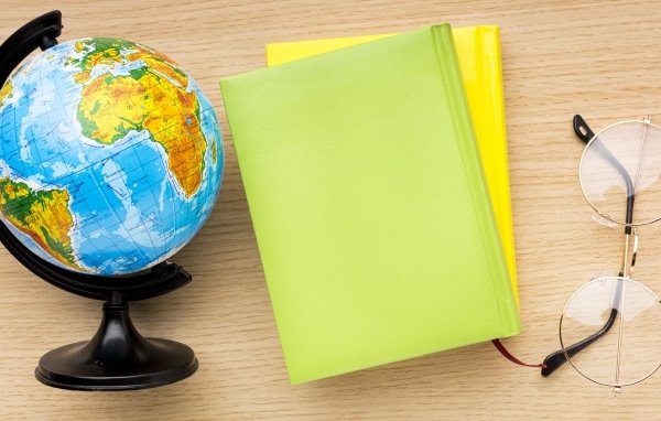 Глобус, тетради и очки на школьной парте