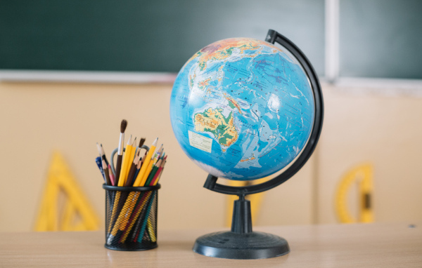 Глобус на столе с карандашами в школе