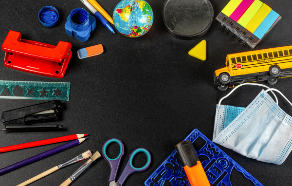 Канцелярские предметы, глобус и игрушечный автобус на черном фоне