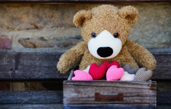 Игрушечный медвежонок с сердечками в деревянном ящике