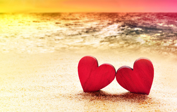 Два красных сердечка на песке на пляже