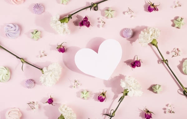 Белое бумажное сердце на розовом фоне с цветами