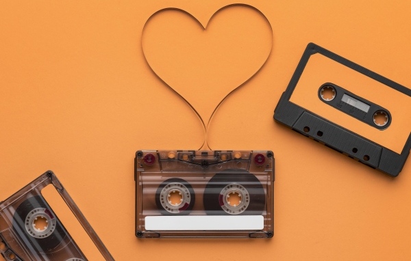 Кассеты и сердце из ленты на оранжевом фоне