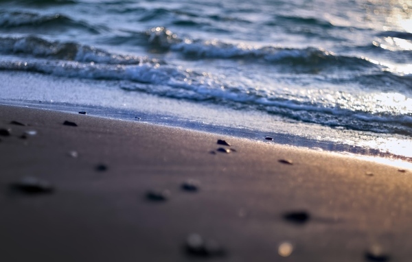 Мокрый морской песок омывает вода