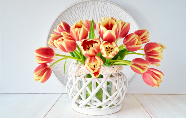 Красивый букет оранжевых тюльпанов в белой вазе на столе