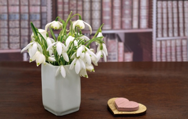 Букет белых подснежников в вазе на столе с сердечками