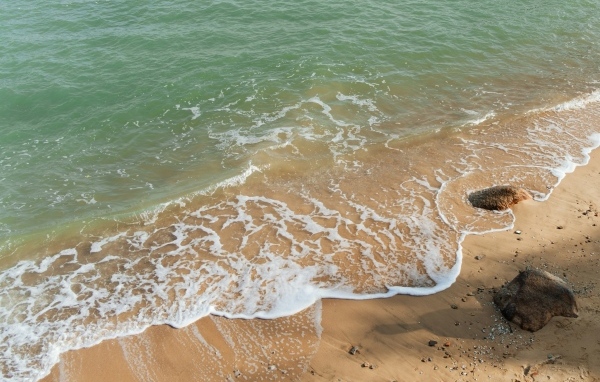 Красивая бирюзовая морская вода с белой пеной на песке